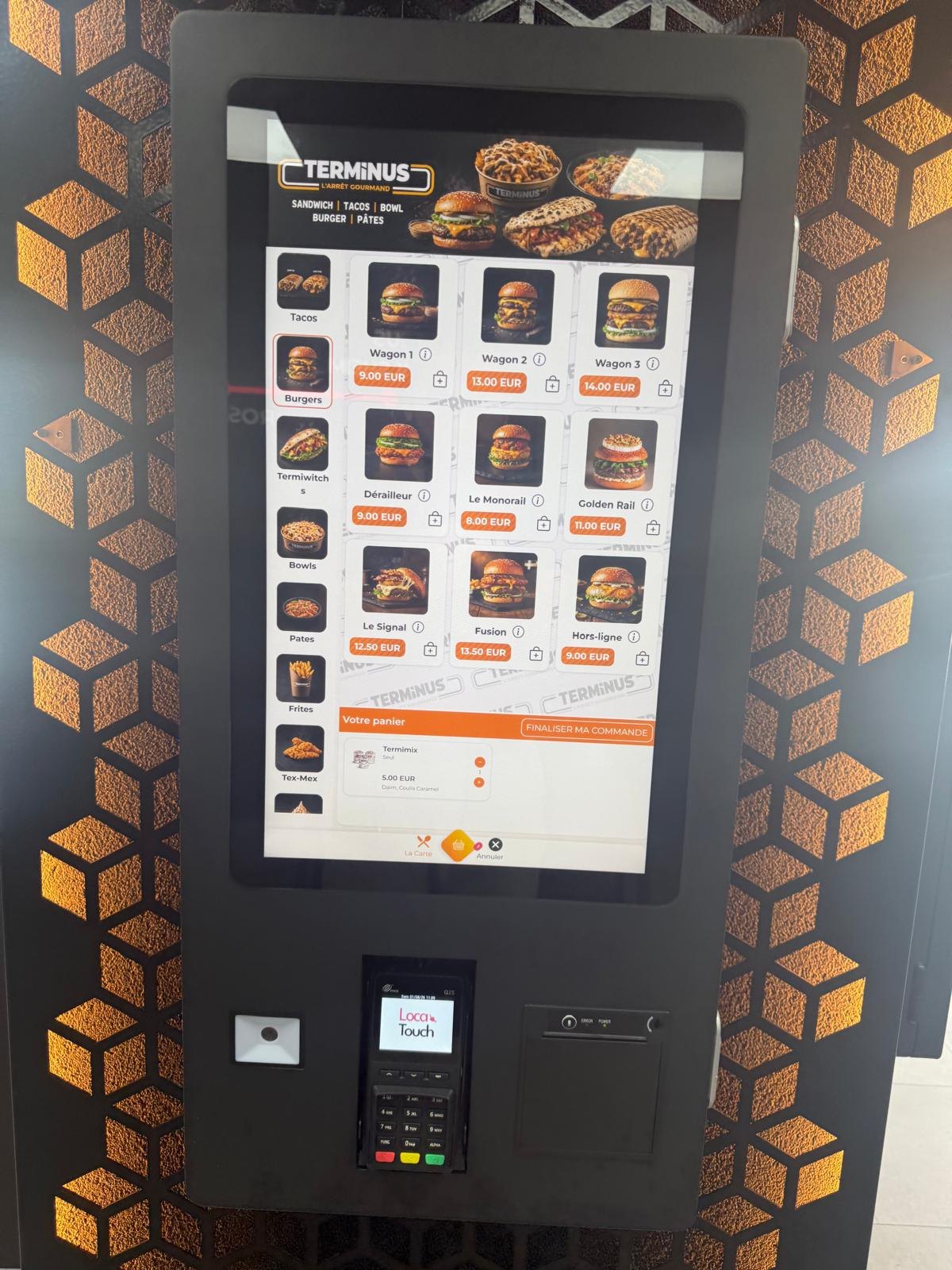 Borne de commande murale entourée d'un habillage hexagonal orange, menu à l'écran
