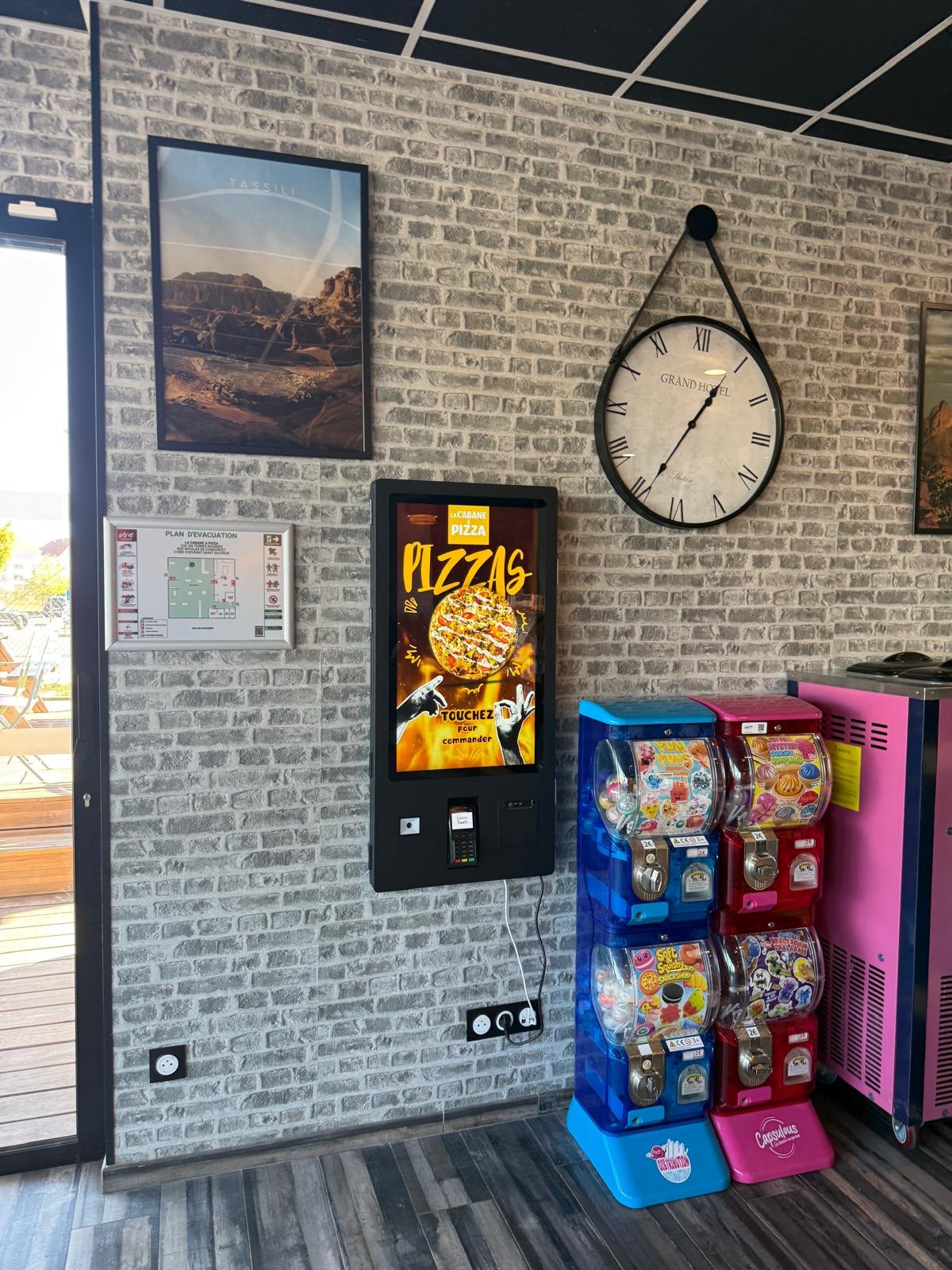 Borne de commande murale pour pizzeria sur un mur de briques grises